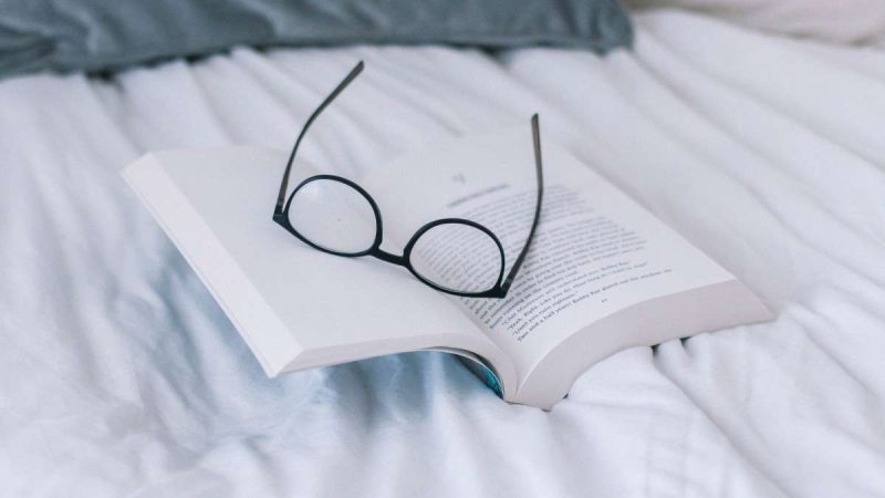 Glasses and book on bed