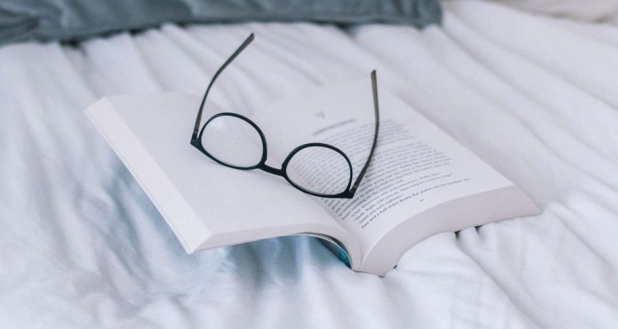 Glasses and book on bed