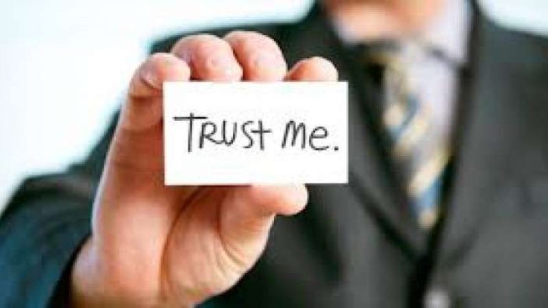 Man with holding card saying Trust Me