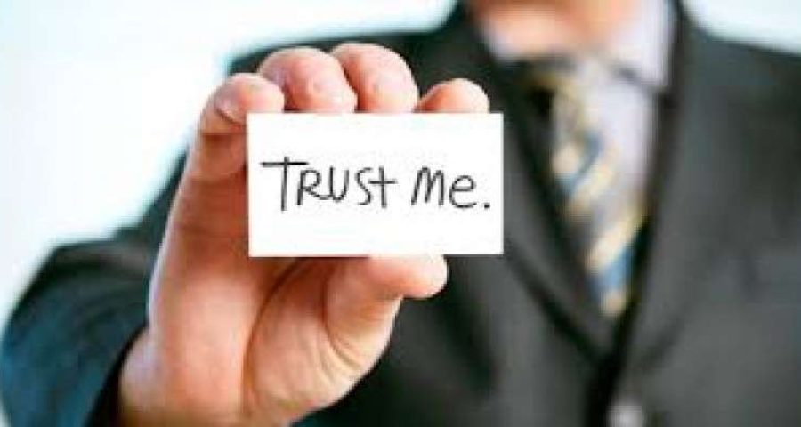 Man with holding card saying Trust Me